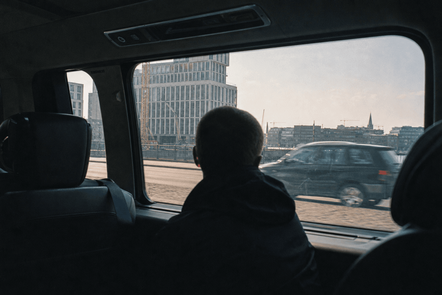 Passagers de dos regardant le paysage urbain belge par la fenêtre d'un van premium
